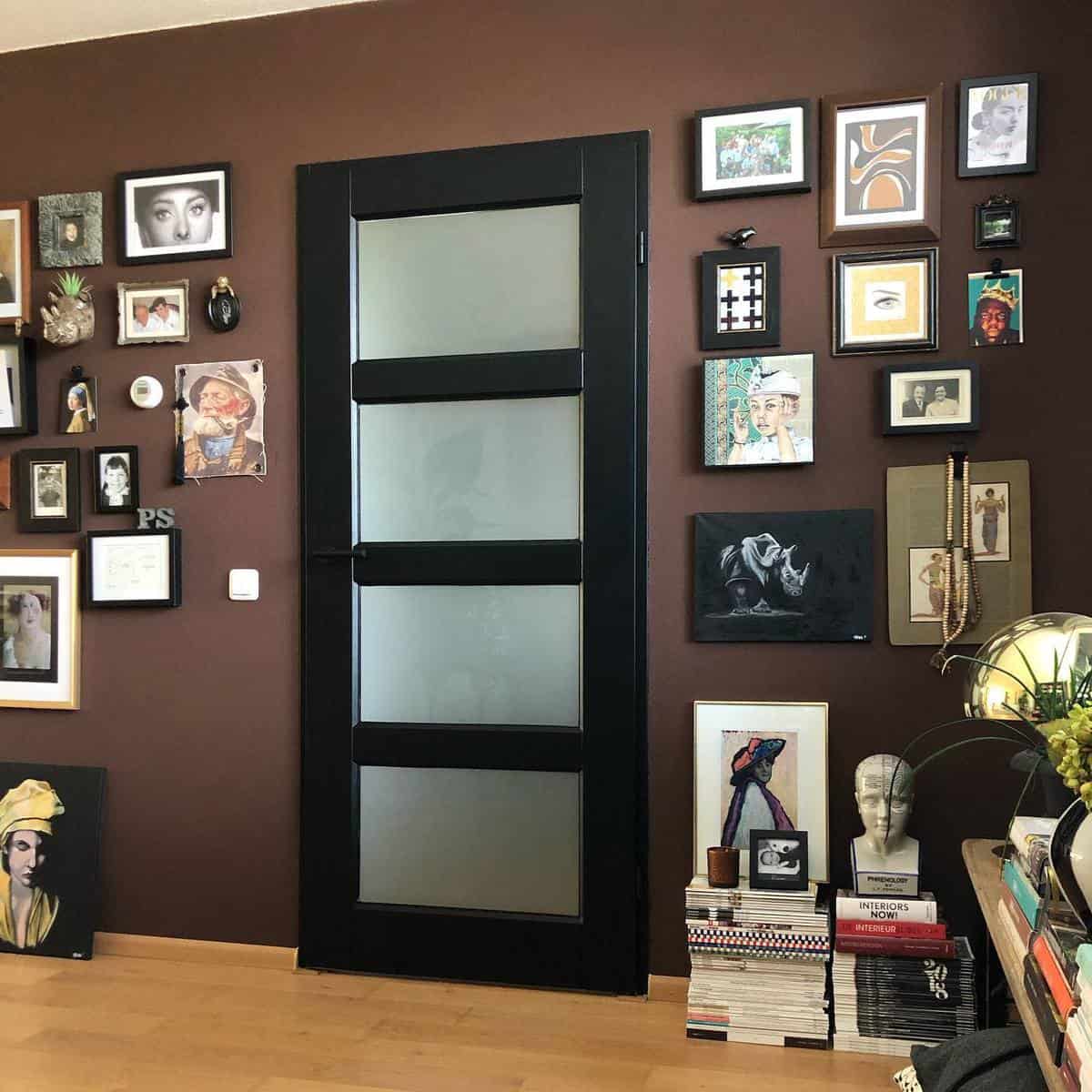 Brown accent wall with framed pictures, black accent door