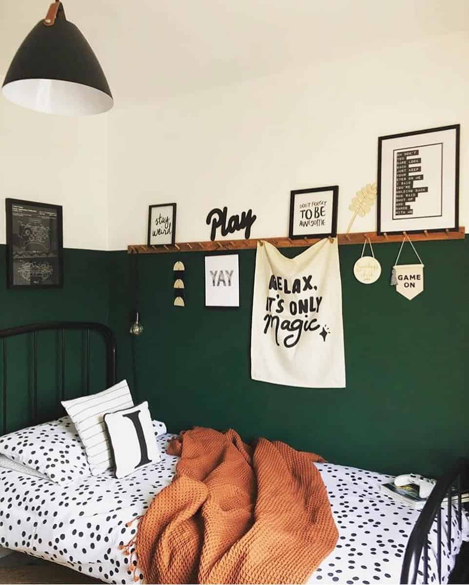 Two-tone green and white bedroom walls, wall hooks, framed artwork, black bed frame
