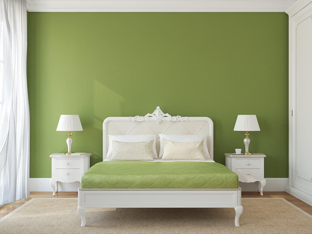 Classic green accent wall in bedroom, elegant white bed frame and nightstands 