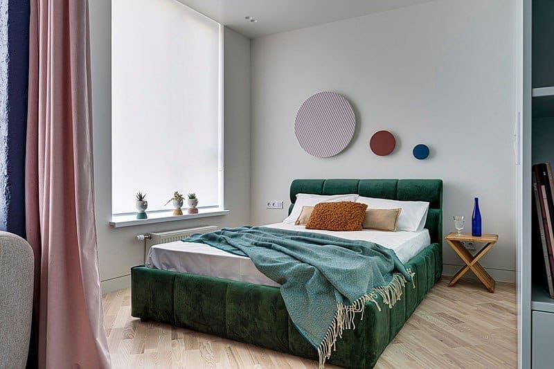 Modern guest room with green bed, circular wall art side table 