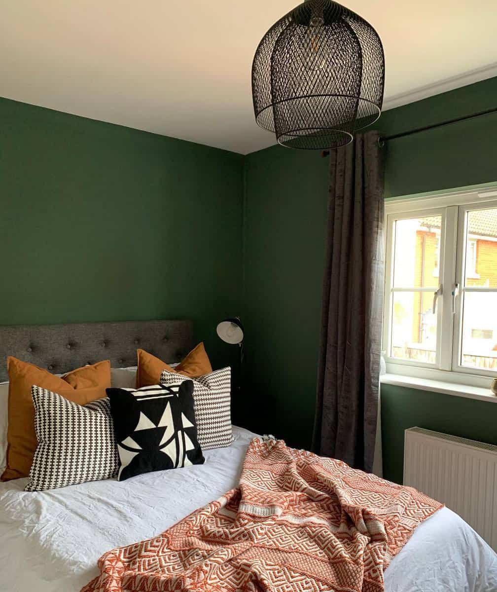 Green guest room with earthy pillows and bedspread 