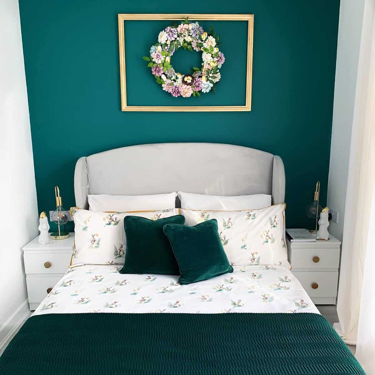 small green accent wall bedroom, gray headboard, gold framed wreath 