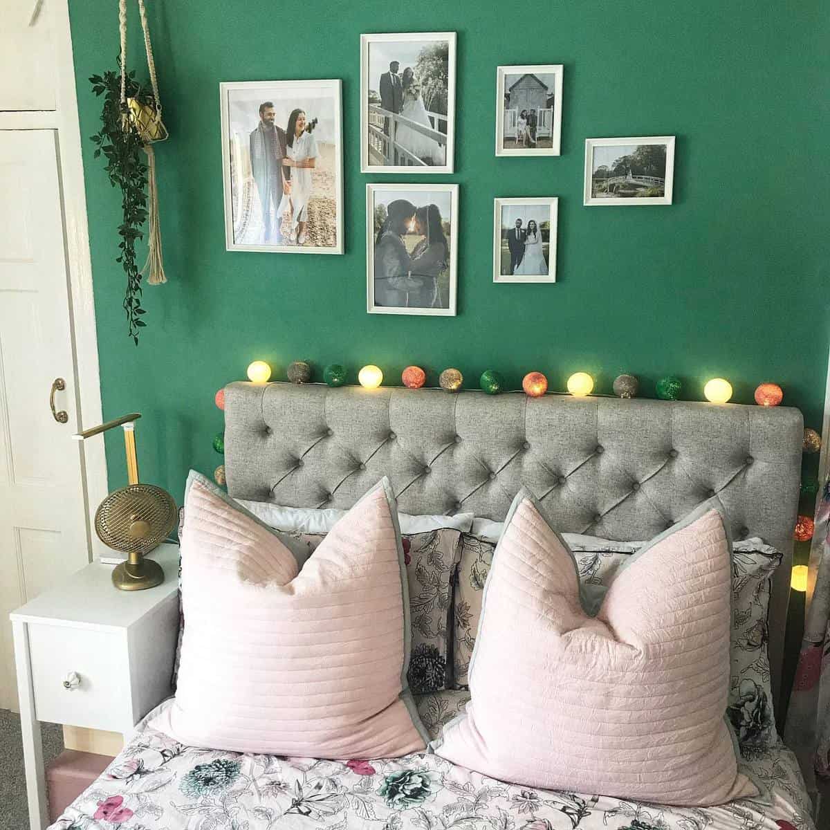 Master bedroom, green accent wall, framed wedding photos, string lights, gray headboard 