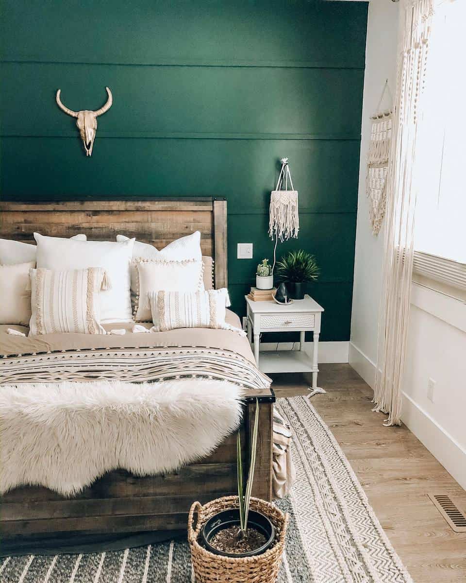 Boho bedroom, green accent wall, wooden bed frame, white nightstand, animal skull