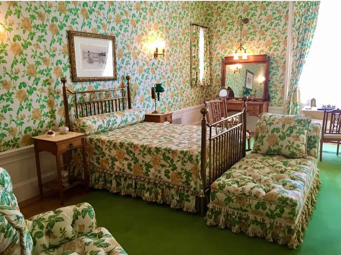 floral green wallpaper, bronze bed frame, green carpet 