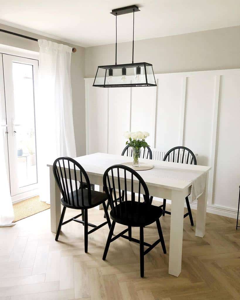white wall paneling, dining room rail, ceiling lighting, black chairs, white table 