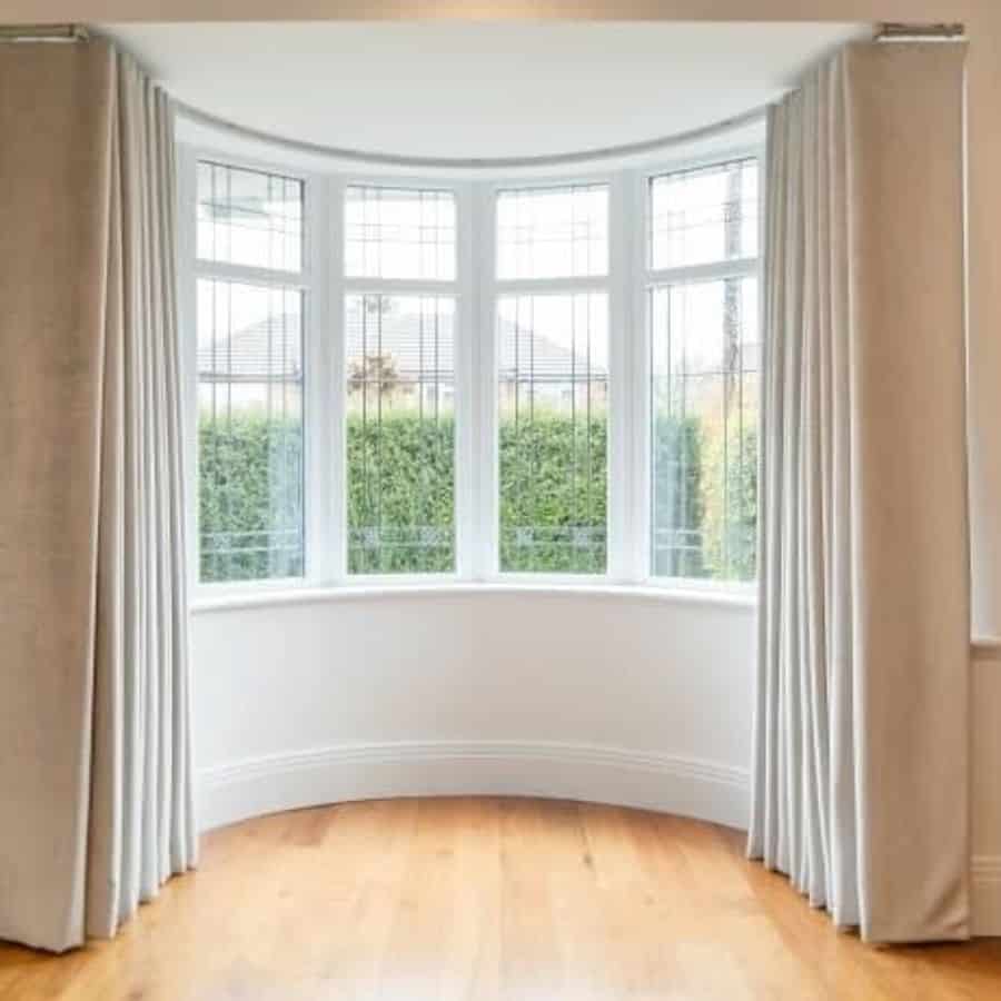 Cream colored curtains for the bay window in the living room