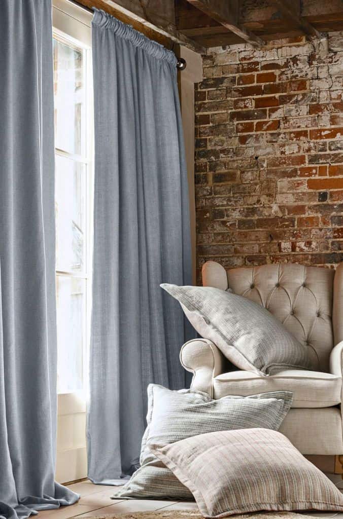 Exposed brick wall, navy blue curtains in living room