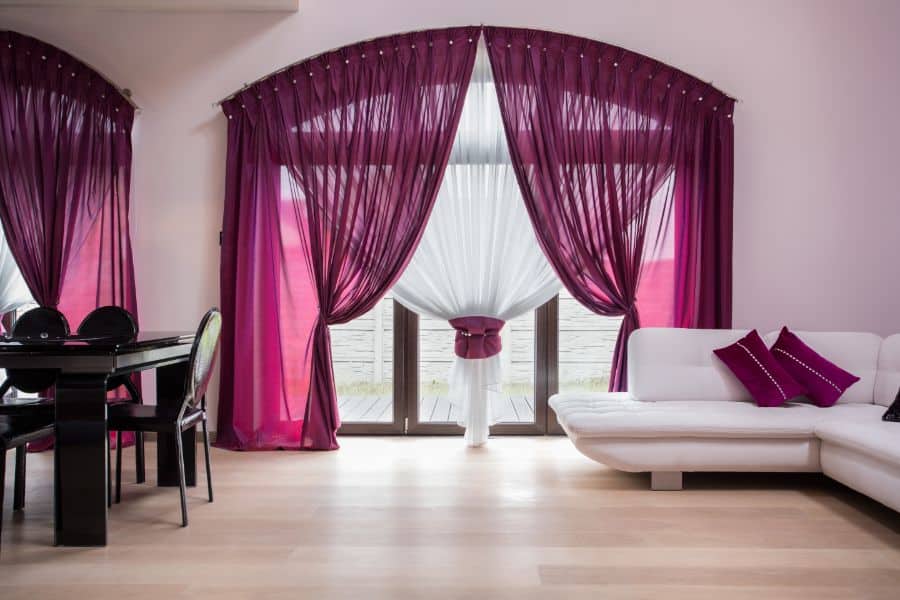 Living room with purple curtains, white sofa and black dining table 