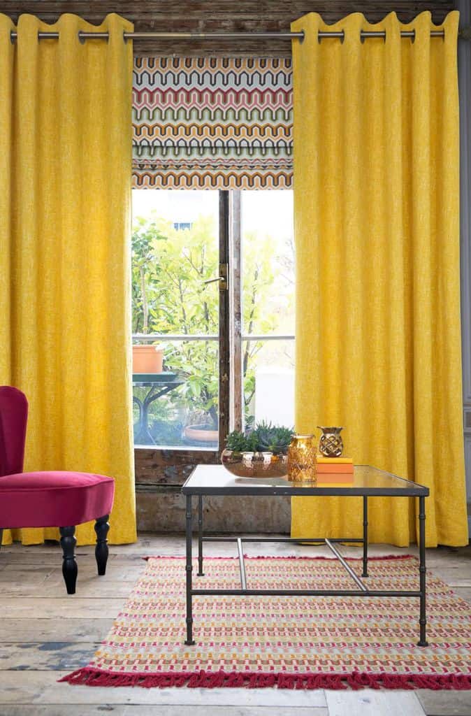 Yellow living room curtains with glass coffee table and red accent chair 