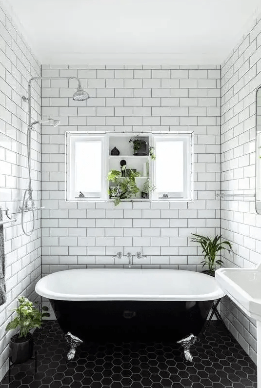 a beautiful black and white bathroom with a white background and black hexagonal tiles, a freestanding sink, a black vintage bathtub and a window