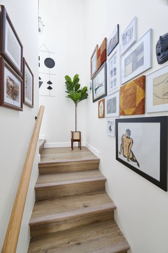 A beautiful gallery wall that spans two walls above the stairs and contains various artwork and graphics is a cool idea