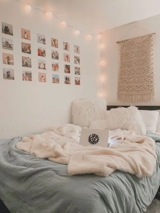 A boho teenager's bedroom features a black bed with white and blue linens, a macrame hanging, lights and a grid pattern gallery wall