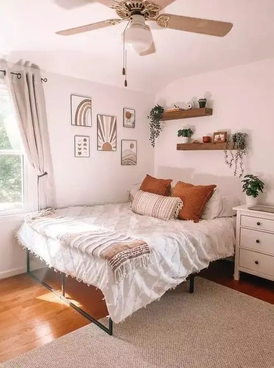 A boho teenager's bedroom with a metal bed, gallery wall, wall shelves, white dresser, potted plants and neutral textiles
