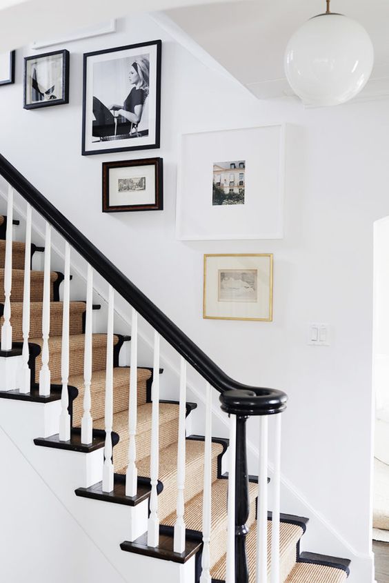 A chic gallery wall with black and white photos and frames and a small piece of art in a gold frame is wow
