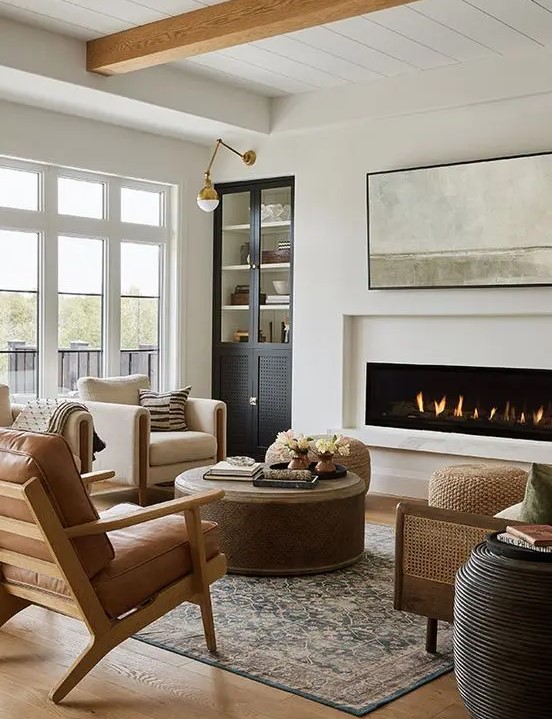 a chic, modern farmhouse living room with a built-in fireplace, built-in storage, neutral fabric and leather armchairs, a sofa and a few tables