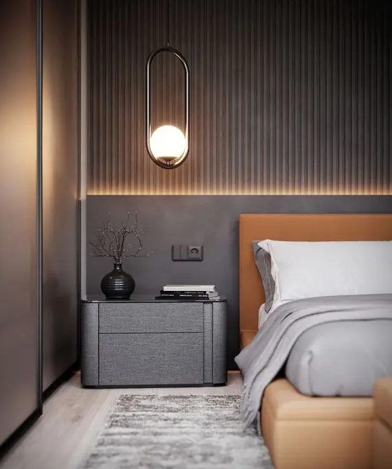 A chic taupe bedroom with an accent wall, an amber leather bed, a dark taupe nightstand, built-in lights and pendant lamps