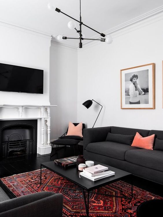 a contrasting living room with a fireplace, a few soot sofas, a coffee table, a chair and a floor lamp