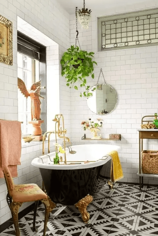 a chic and whimsical bathroom with a beautiful printed tile floor, a black vintage bathtub, a crystal chandelier and vintage furniture and a potted plant
