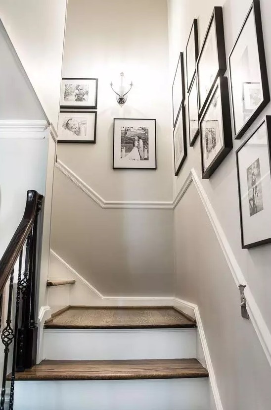 A freely designed gallery wall with matching black frames and black and white family pictures is a beautiful and artistic way to present the photos