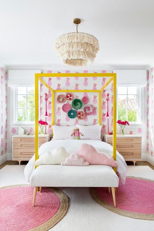 A fun teenage girl's room with bright pineapple wallpaper, a yellow four-poster bed, a statement gallery wall and pink rugs