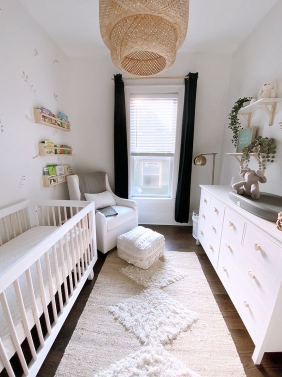a gender neutral nursery with a neutral crib, white dresser, white chair with ottoman and layered rugs