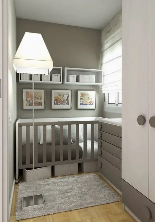 a gray and white small nursery with a built-in crib and a gray dresser that doubles as a changing table, as well as shelves with baskets for storage