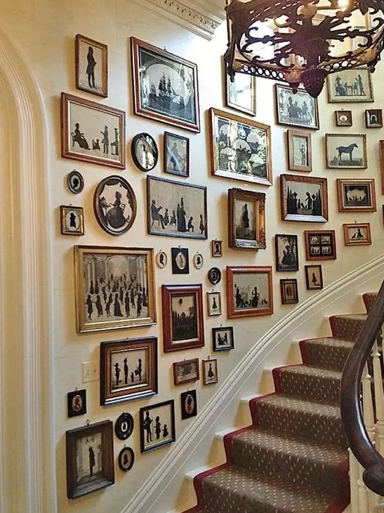 a large gallery wall with mismatched vintage frames and black and white artwork with a strong, elegant vintage touch