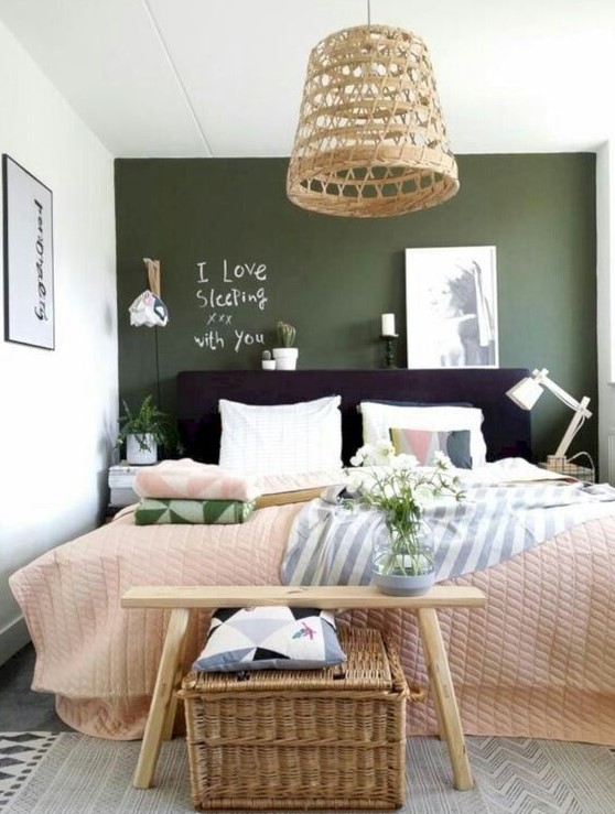 a vibrant bedroom with a green wall, a black bed, neutral and printed linens, a bench, a woven chest and a woven hanging lamp