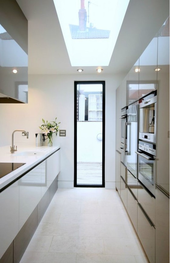 a minimalist white and brown kitchen with a skylight and a door to a balcony, shiny and elegant cabinets and lights