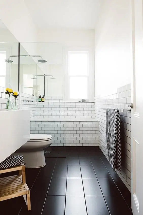 a modern bathroom with white subway tiles and black on the floor, white appliances and a stained ladder