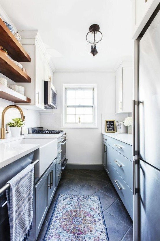 A modern gray and white galley kitchen with open wooden shelves, brass and stainless steel, and a boho rug looks cool