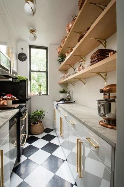 a modern, narrow kitchen with sleek white cabinets and stone countertops, open shelving, potted plants and a checkered floor