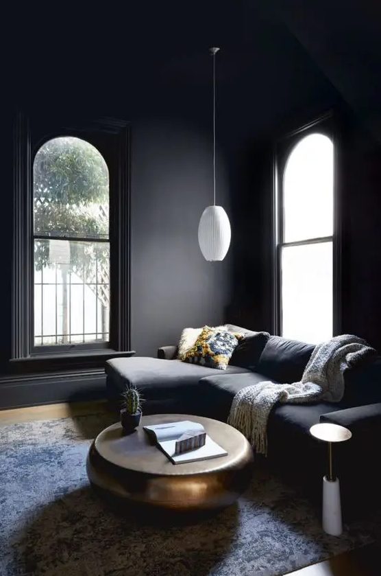 an atmospheric living room with sooty walls and a matching seating area, a metal coffee table and a white pendant lamp