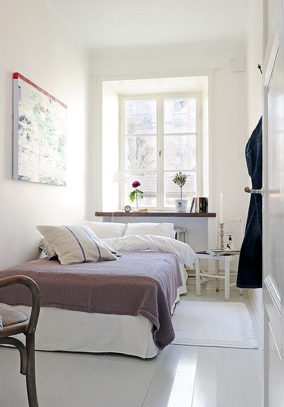 a narrow Scandinavian bedroom with a bed, a windowsill as storage space, a stool as a bedside table and some decorations