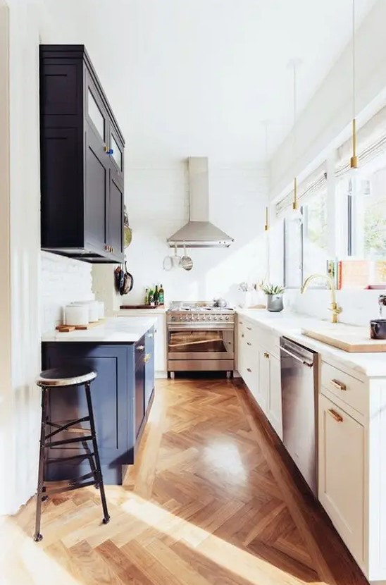 a narrow kitchen with white and navy shaker-style cabinets, white stone countertops, and lots of natural light streaming through the windows