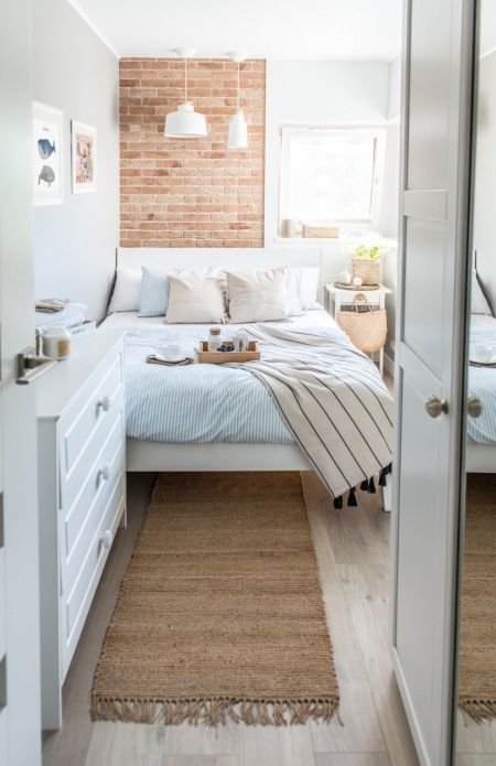 a narrow, light-filled bedroom with a dresser, a bed with neutral linens, pendant lamps and a nightstand with some decor
