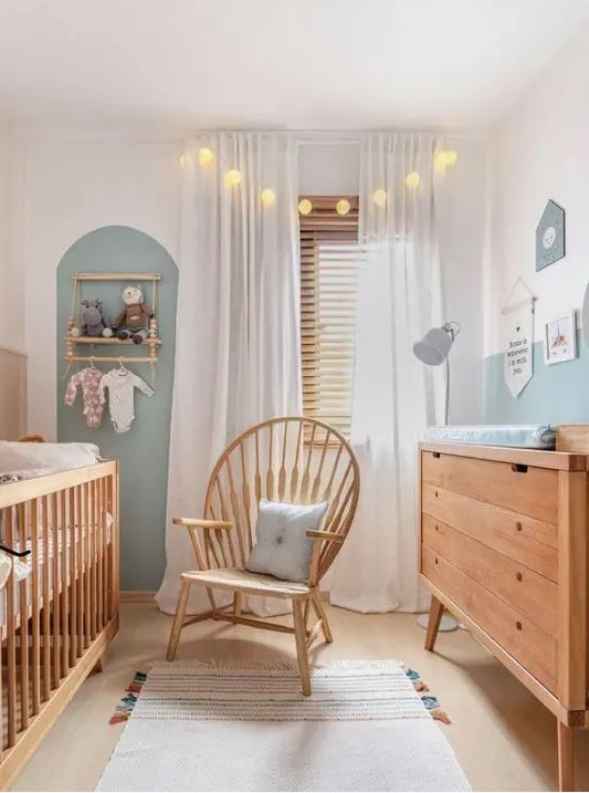 A neutral and pastel nursery with stained furniture, an accent wall, a makeshift closet, and lights and lamps is very inviting