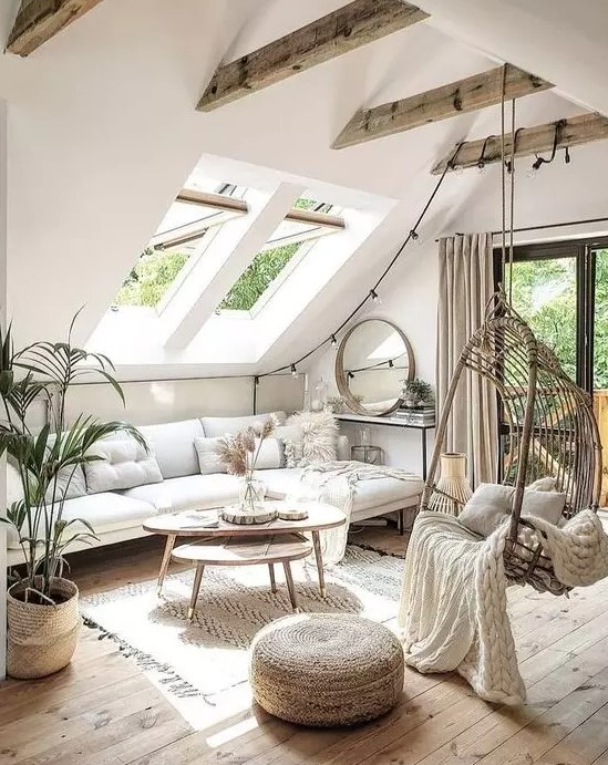 A neutral boho living room in the attic with skylights, beams, a hanging chair and wooden coffee tables