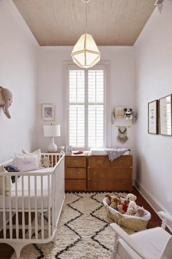 A neutral, mid-century modern nursery with a stained dresser, a white crib, a printed rug, and some toys in baskets is a cool idea