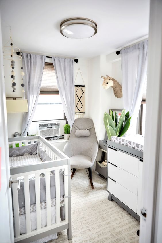 a neutral, modern nursery with a gray and white crib, matching dresser, gray chair, light gray curtains and some decorations