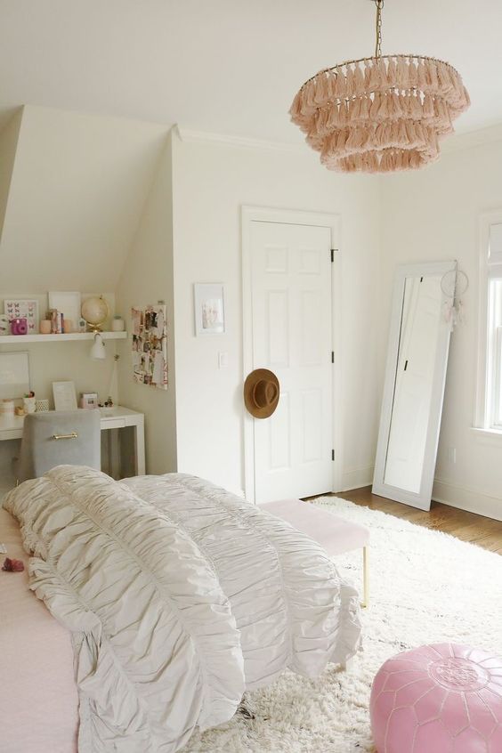 A neutral, modern teenage girl's room with a dressing table and a chair in the corner, some shelves, a bed and a pink bench and a pink stool