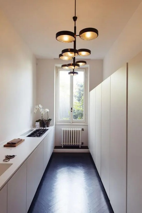 a neutral, narrow kitchen with low and high cabinets on the second wall, statement lamps and built-in appliances