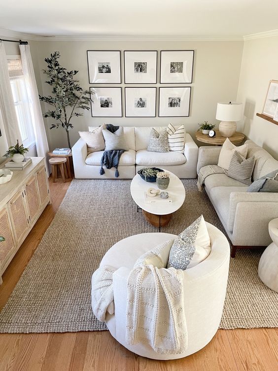 a neutral small living room with a cane TV, neutral sofas, a chair, a coffee table, a gallery wall and some decor and plants