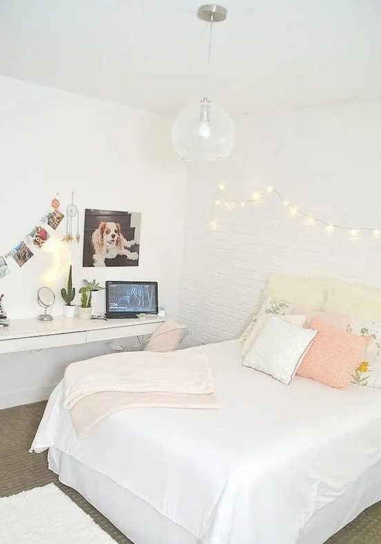 a neutral teen room with a floating desk and dressing table, a bed with pastel pillows and lights on the wall