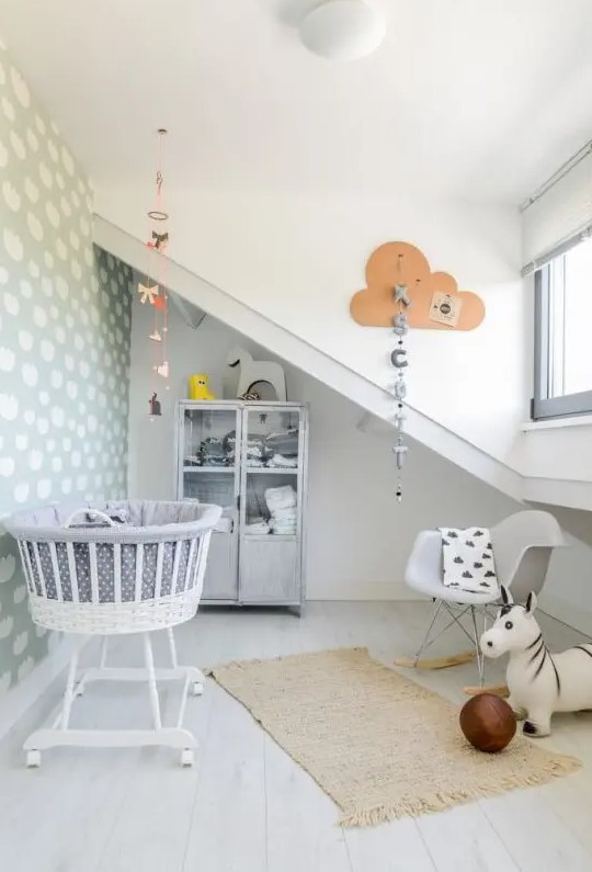 a neutral, fun nursery with gray walls, a cloud accent wall, printed textiles, mobiles and garland