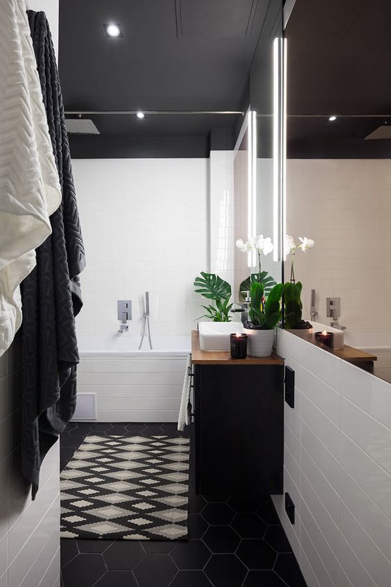 a pretty black and white bathroom with white tiles and a black ceiling, a black hexagon tile floor, a black vanity and a mirror