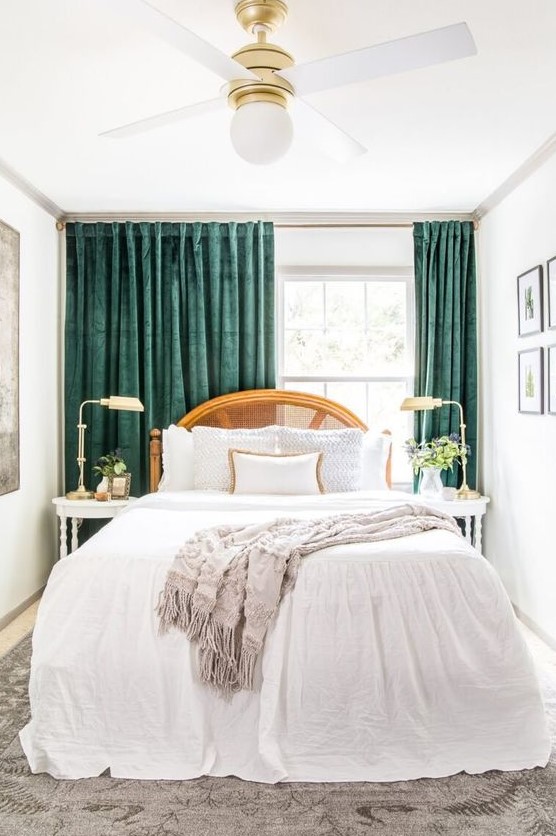 a sophisticated small bedroom with a bed with a can headboard and neutral linens, elegant bedside tables and lamps and amazing green curtains