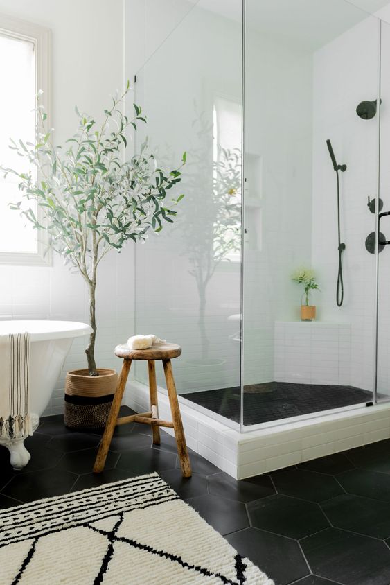 a tranquil bathroom with white tiles on the walls and black hexagonal tiles on the floor, a claw-foot bathtub and a shower area