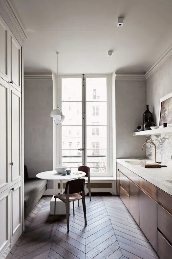 a quiet, narrow kitchen with metal cabinets and stone slab countertops, a marble backsplash, a sofa, a table and chairs